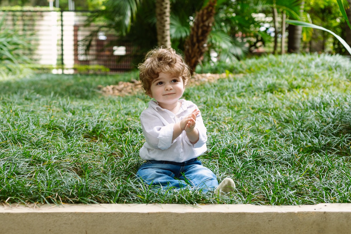 Criança sentada na grama do jardim